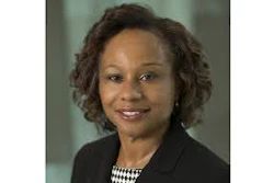 Professional headshot of a woman in business attire with checkered blouse and dark blazer