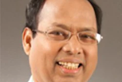Professional headshot of a smiling man wearing glasses and light-colored shirt
