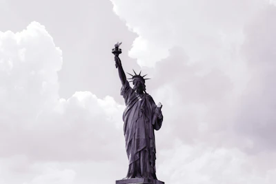 Statue of Liberty standing tall against a cloudy sky with raised torch and crown