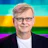 Professional headshot of a man with glasses smiling against a vibrant rainbow gradient background