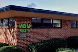 WBAV 903 FM radio station signage on brick building exterior with windows and hedges
