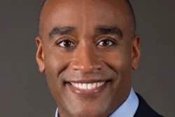 Professional headshot of a smiling man in business attire with blue shirt and tie