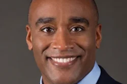 Professional headshot of a smiling man in business attire with blue shirt and tie