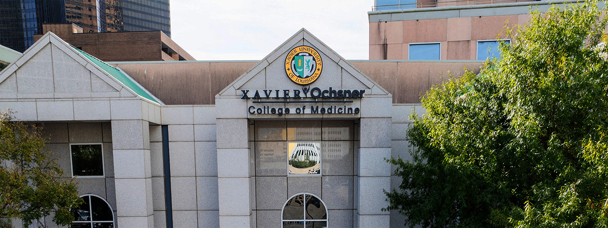 Xavier University College of Medicine building entrance with institutional seal and signage on white stone facade